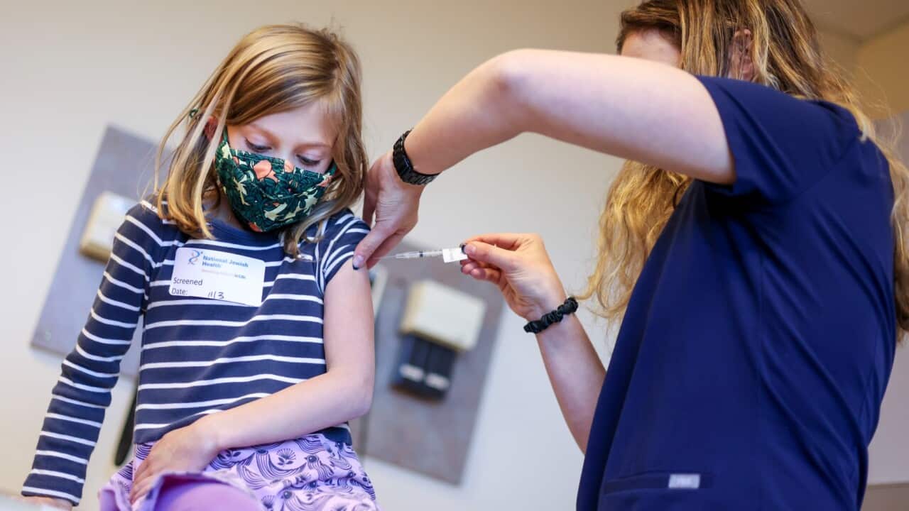 National Jewish Health registered nurse Lindsay Waldman, right, administers a pediatric COVID-19 vaccine to Coco Peikin, 6,
