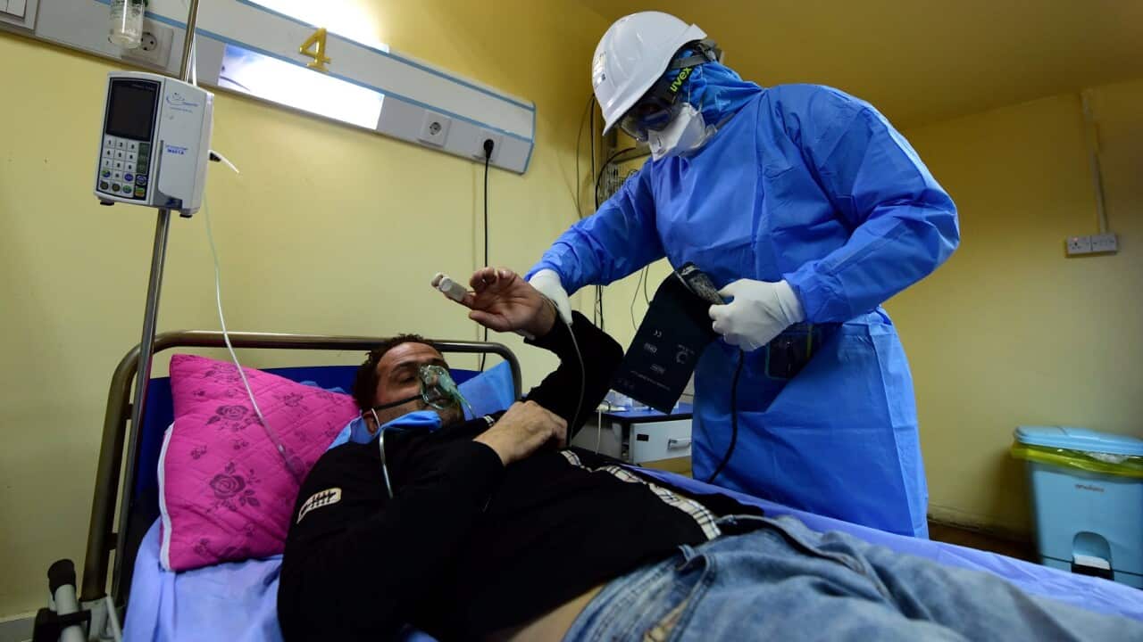 An Iraqi nurse wearing protective gear treats a patient with COVID-19 in a Baghdad hospital
