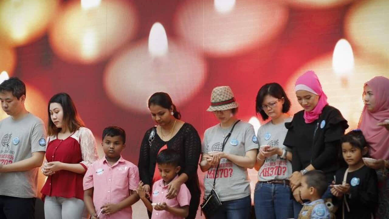 Relative of passengers on bow their heads in a minute's silence