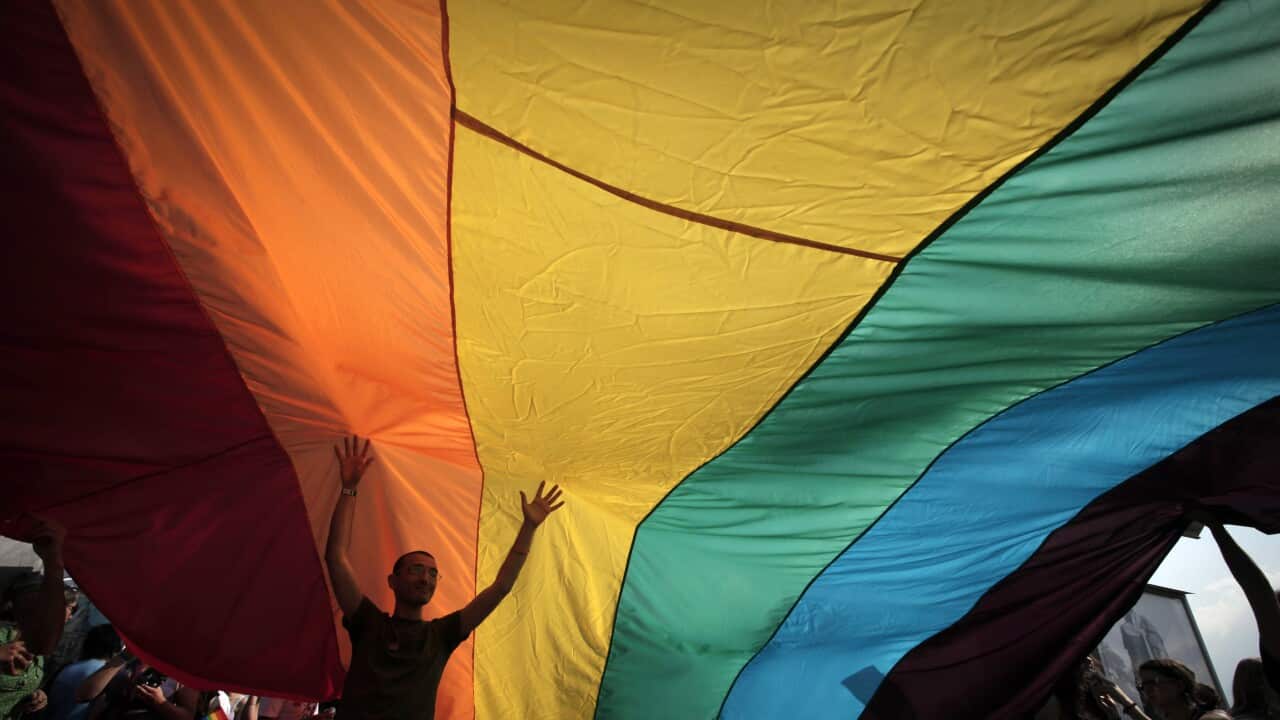 A man is seen underneath the rainbow flag