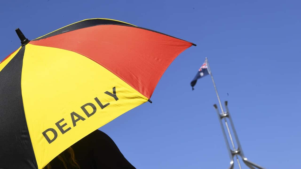 An umbrella in the colours of the Aboriginal flag and the word 'deadly'