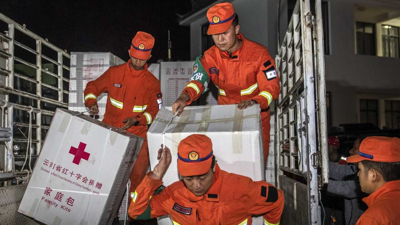 Men in orange boiler suits carrying white boxes