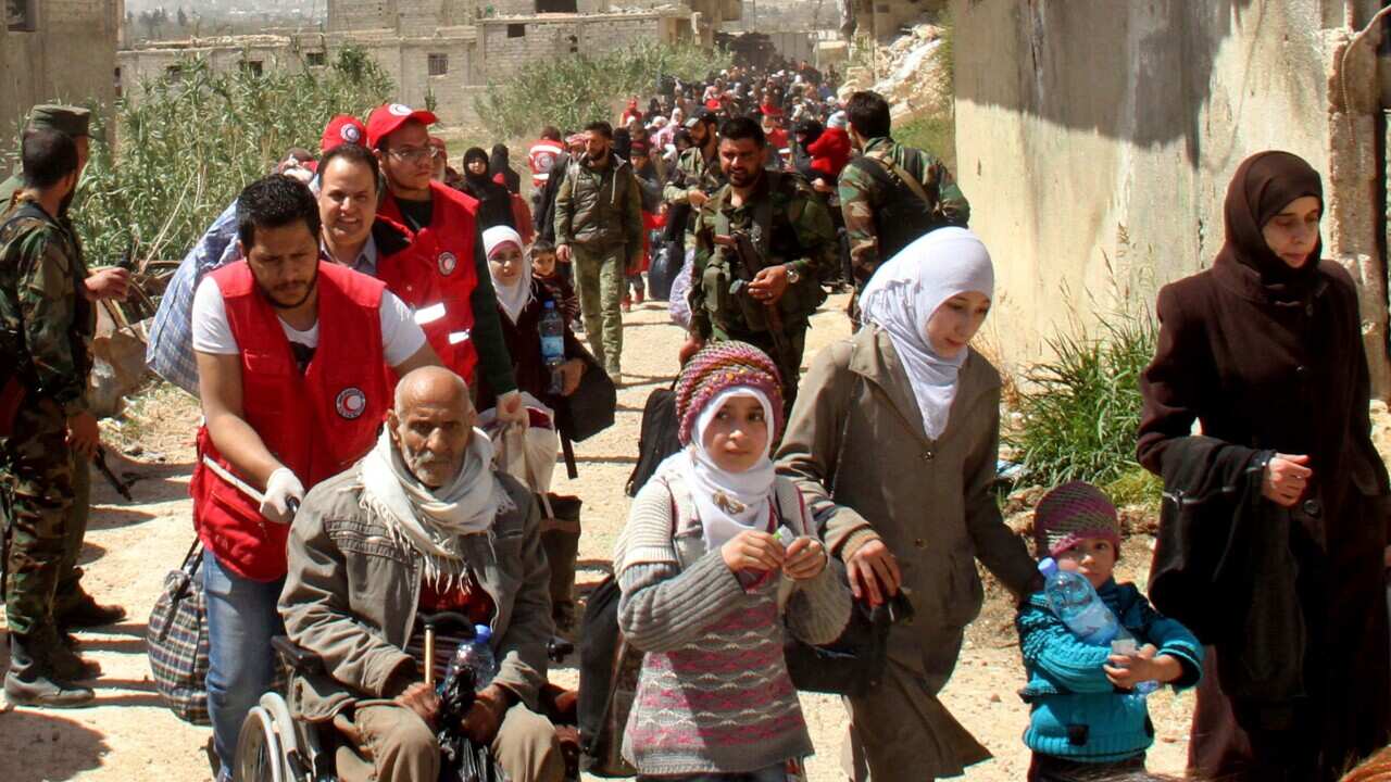 This photo released by the Syrian official news agency SANA, shows civilians carrying their belongings leaving towns and villages.
