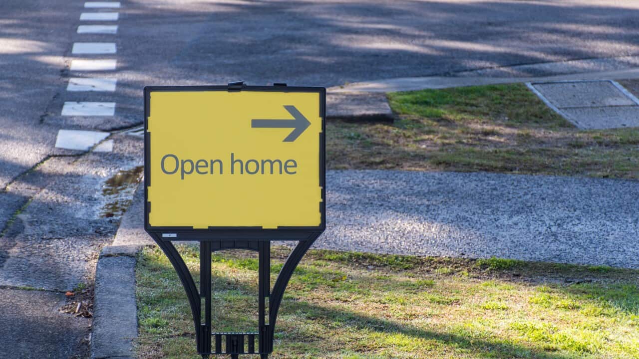 Yellow open home sign with black arrow on the street.