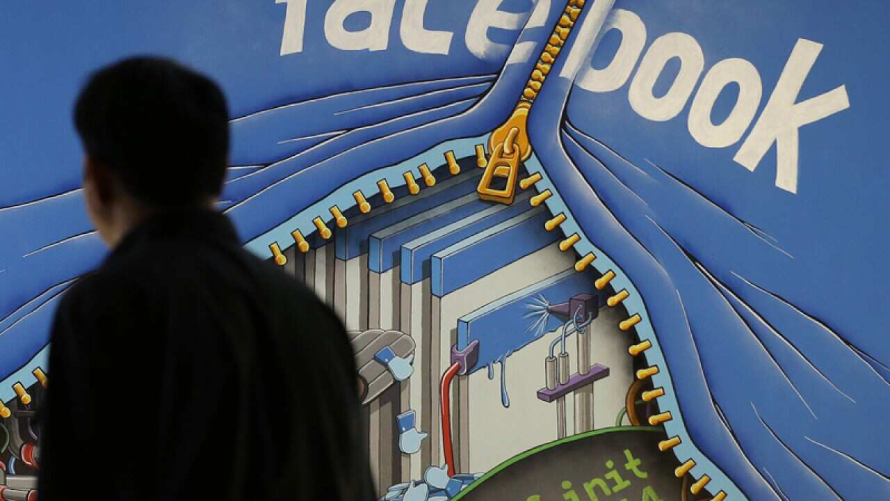 Man walks past a mural in an office on the Facebook campus