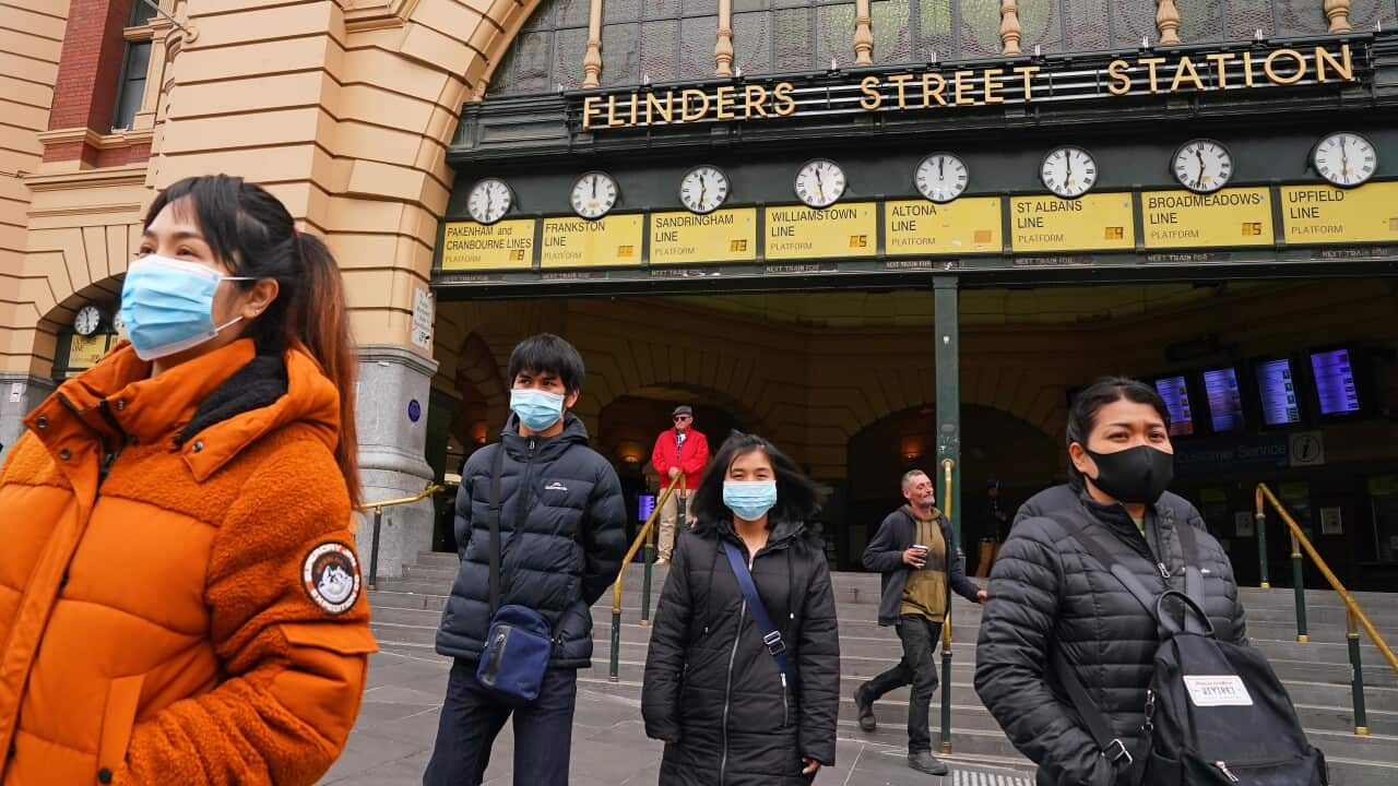 People leave Flinders Street Station wearing face masks
