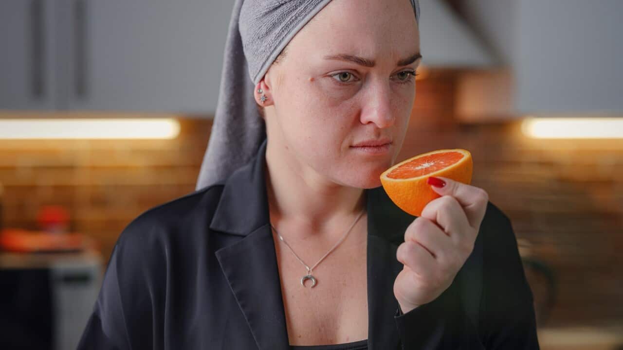 Sick woman trying to sense smell of fresh orange