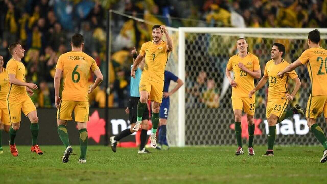 Socceroos players celebrate after scoring a goal against Greece