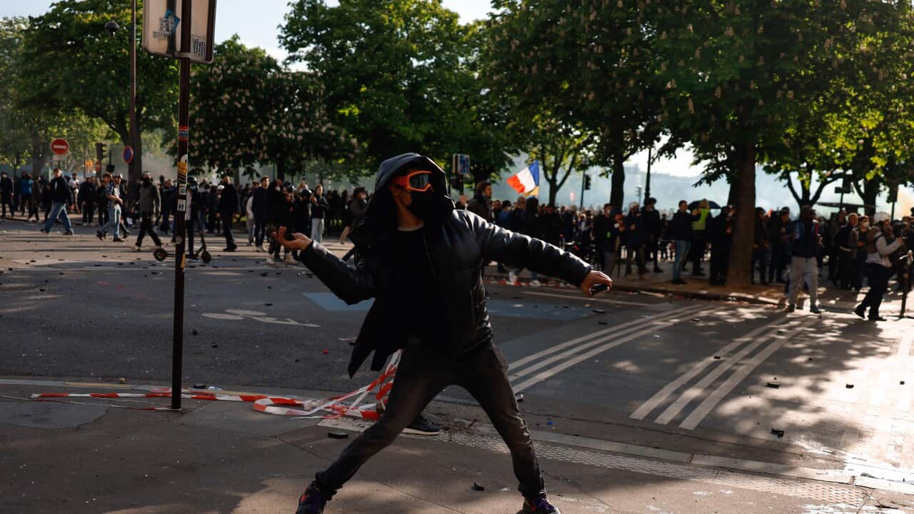 A demonstrator throws an object at police during May Day protest.