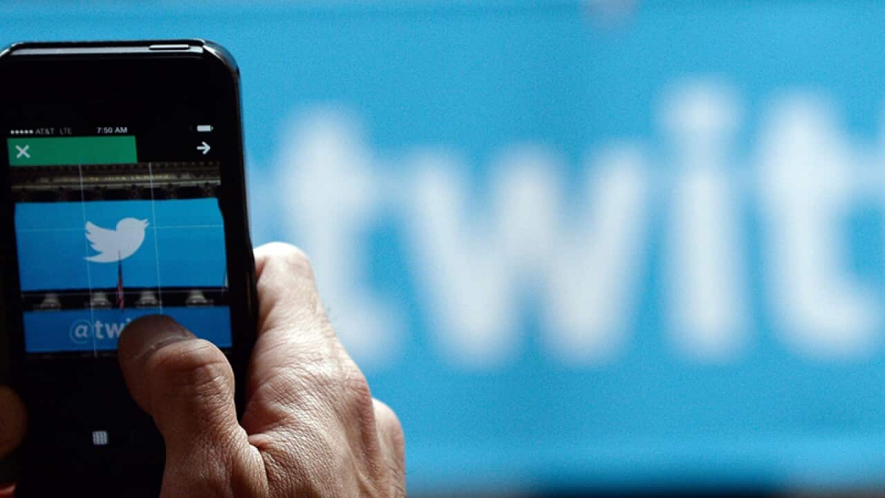 A passer-by photographs the Twitter logo