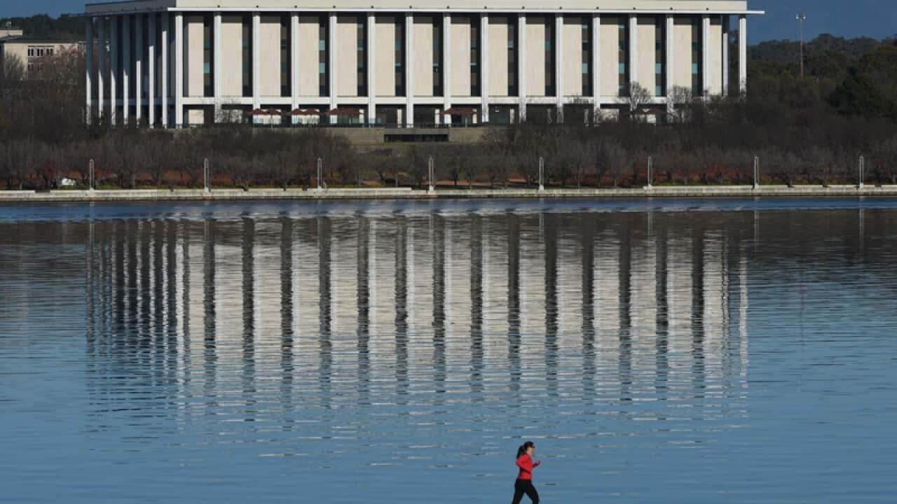 A jogger runs past the National Library of Australia in Canberra
