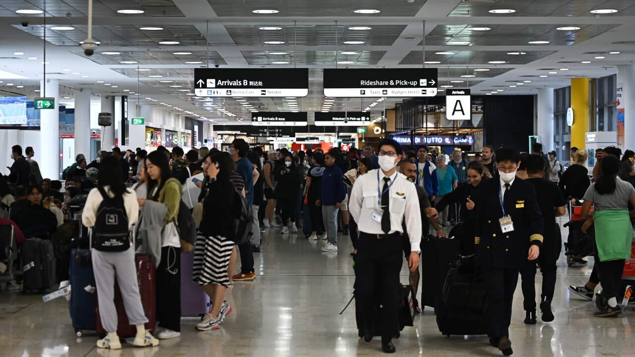 Travellers standing in an airport arrivals hall.