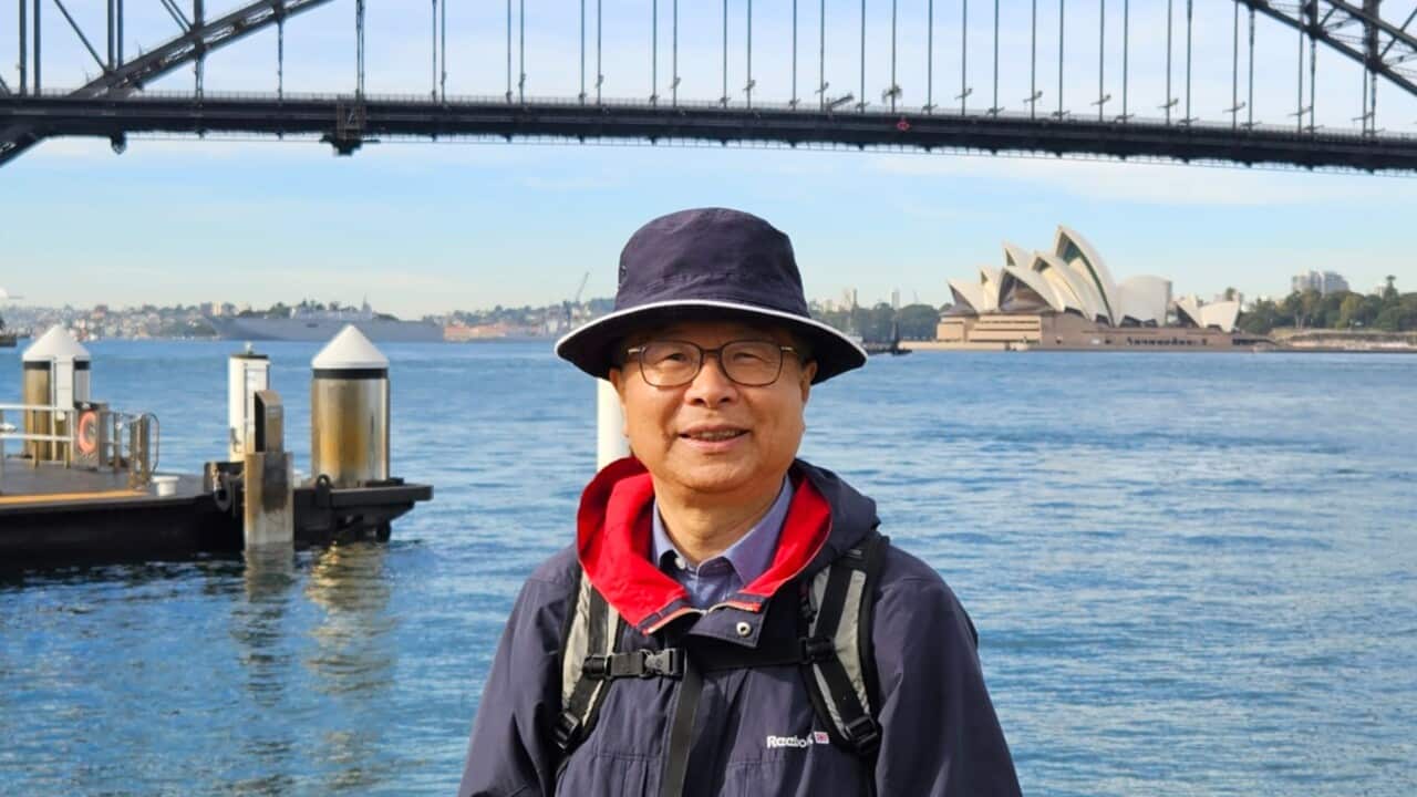 A man stands in front of the Sydney Harbour Bridge