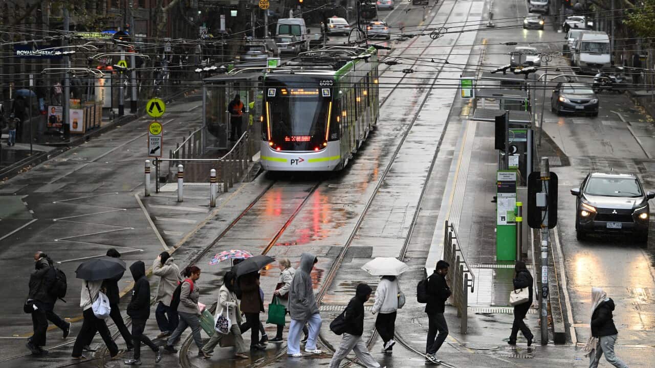 People with umbrellas cross a wet street in Melbourne.