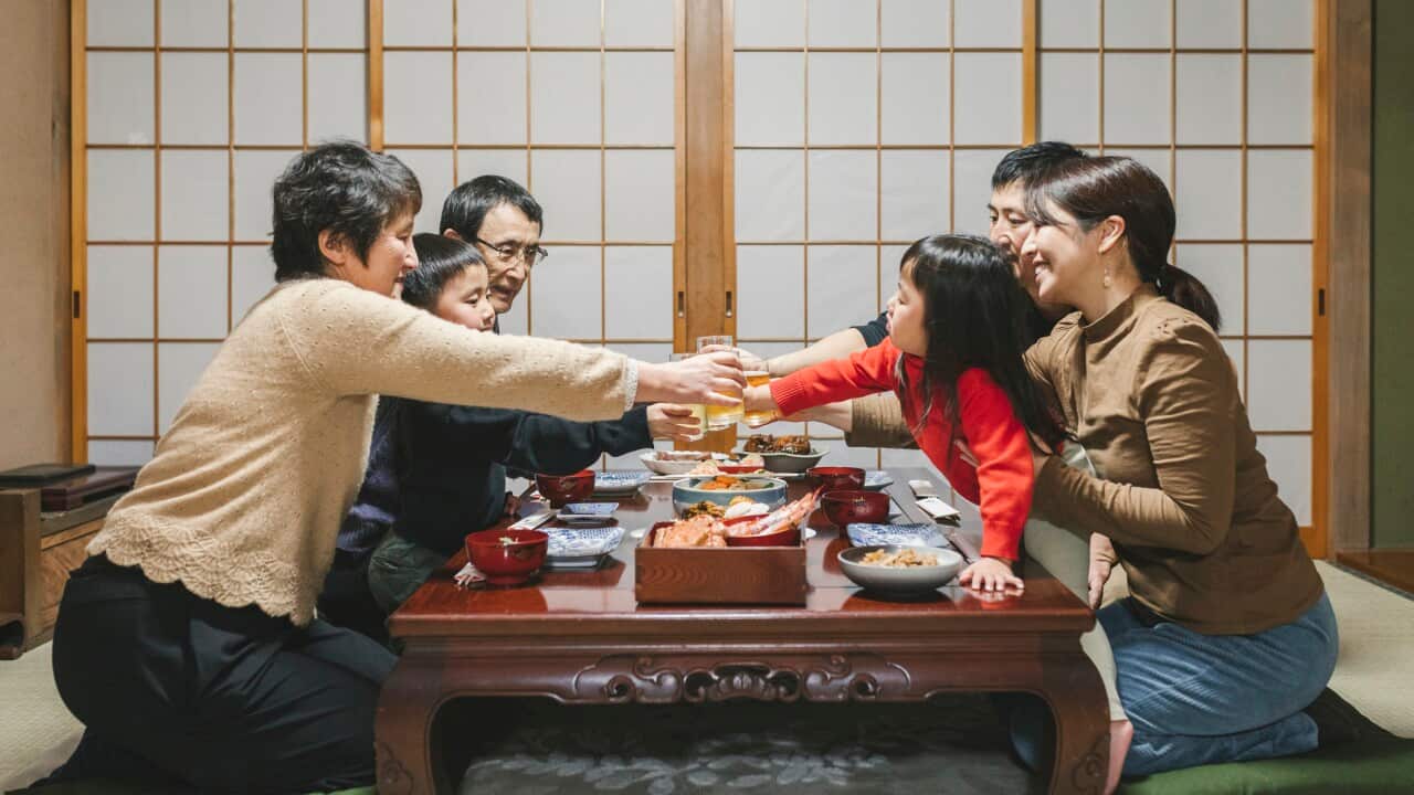 Japanese mulit generation family drinking a toast before eating Osechi Ryori, Japanese New Year dishes, on the dining table in Japanese room