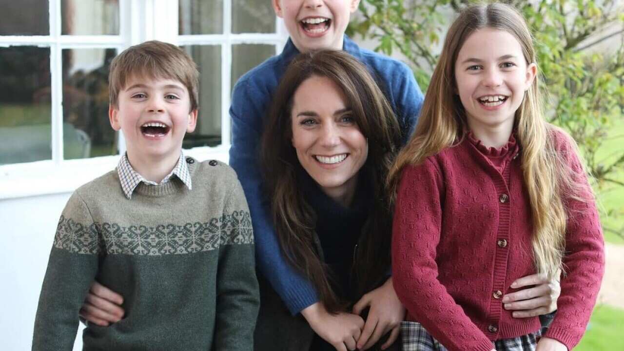 A woman posing for a photo with her two sons and daughter.