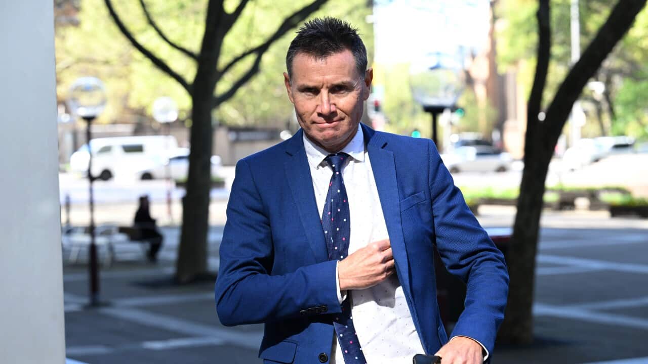 A white man in a blue suit and tie walking down a street