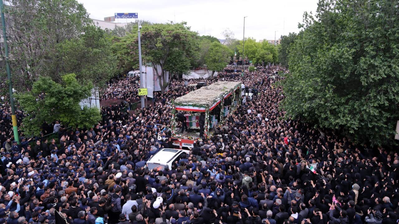 A large mass of people marching with a truck covered in flowers in the centre of them.
