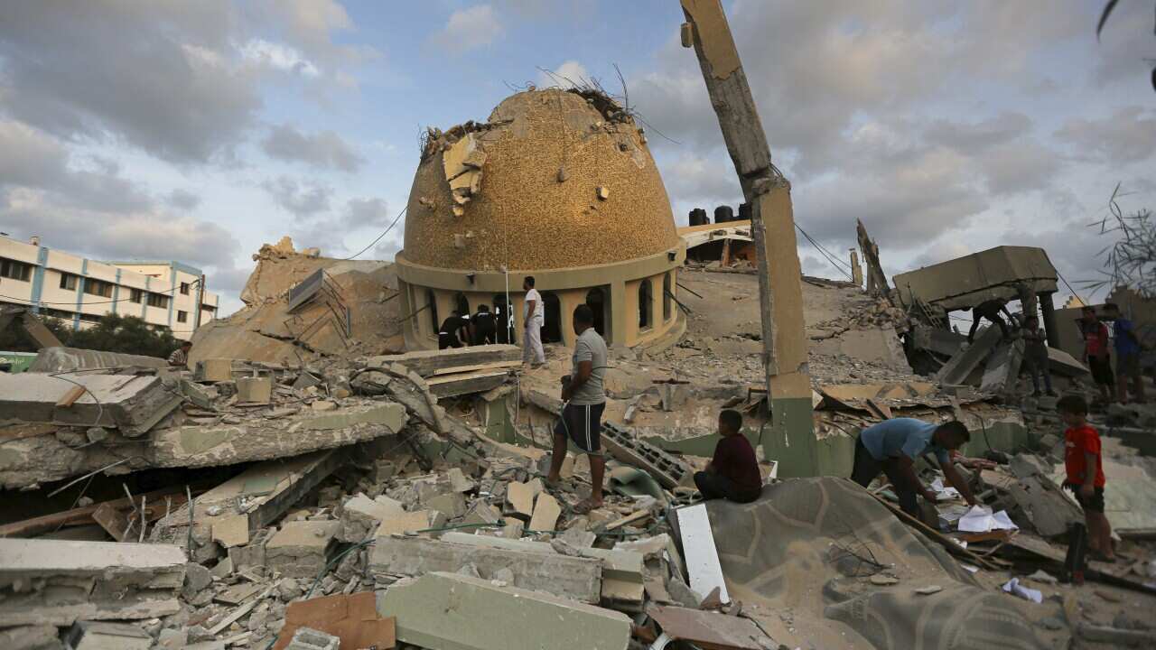 People stand outside a mosque destroyed in an Israeli air strike in Khan Younis, Gaza Strip, Sunday, Oct.8, 2023.