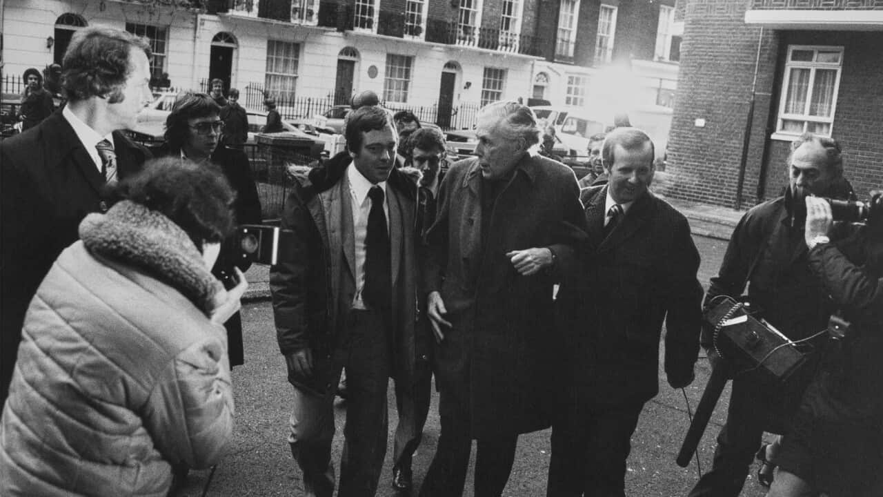 Anthony Blunt is besieged by photographers following his exposure as a spy (Getty)
