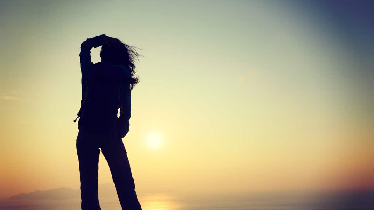 freedom woman with backpack standing on sunrise windy coast