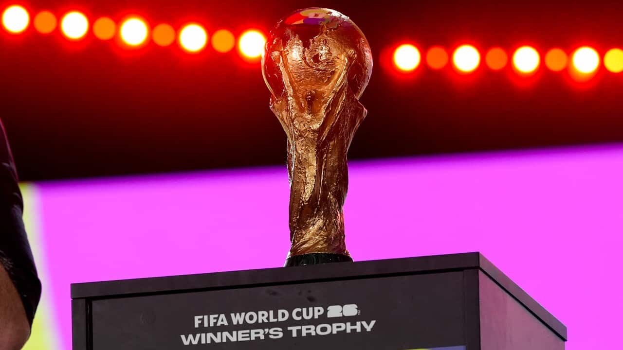 The FIFA World Cup trophy on display during an event, with bright lights in the background.