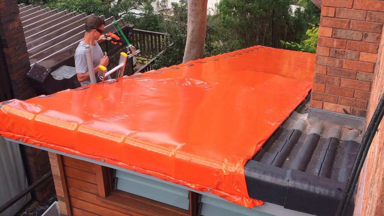 StormSeal emergency protection being deployed on a damaged roof
