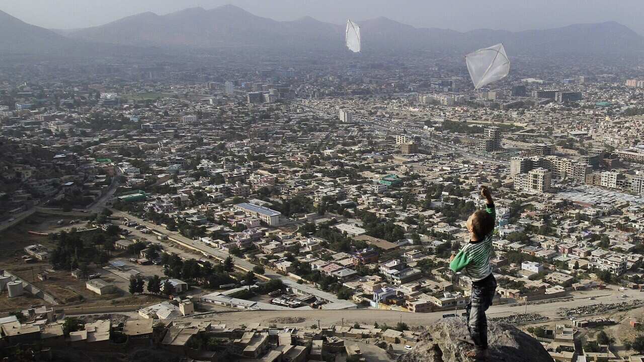 An Afghan boy flies a kite on top of a mountain in Kabul, Afghanistan.