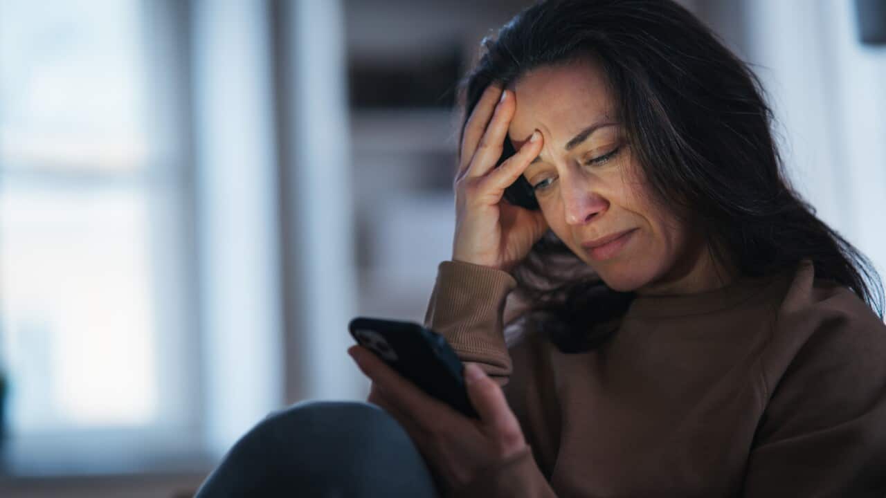 Woman reading an unpleasant text message and crying.