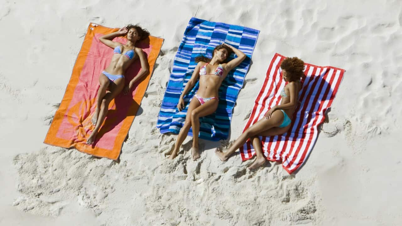 Women in bikini lying on towels sunbathing