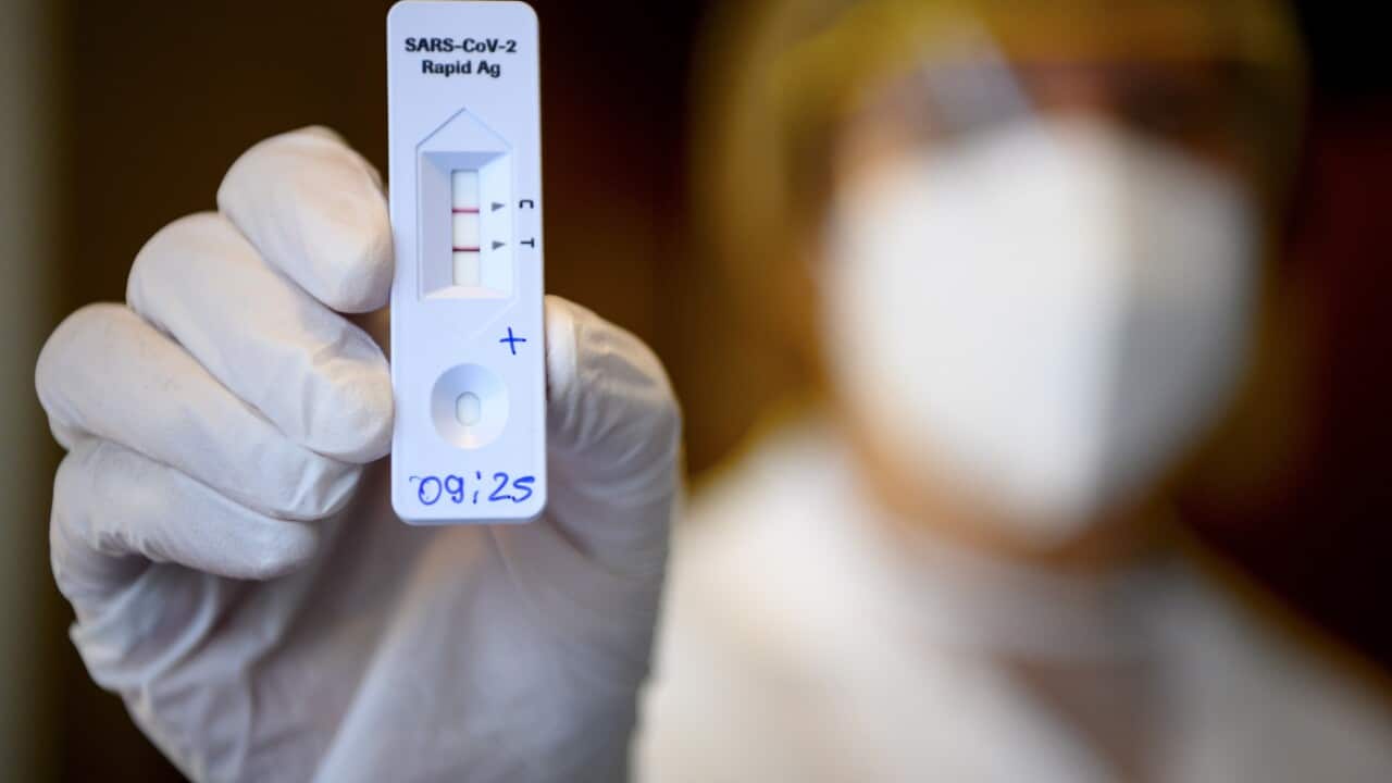 A health worker shows a positive SARS-CoV-2 Rapid Antigen Test from the Swiss multinational healthcare company Roche just after collecting a nose swab