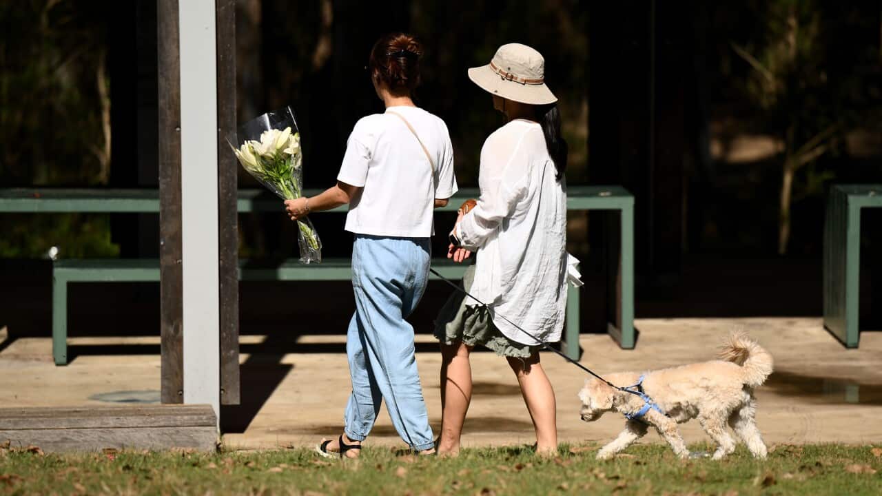 Women laying flowers at the scene of a stabbing