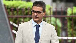 A man wearing a suit, tie, and glasses walking outside.