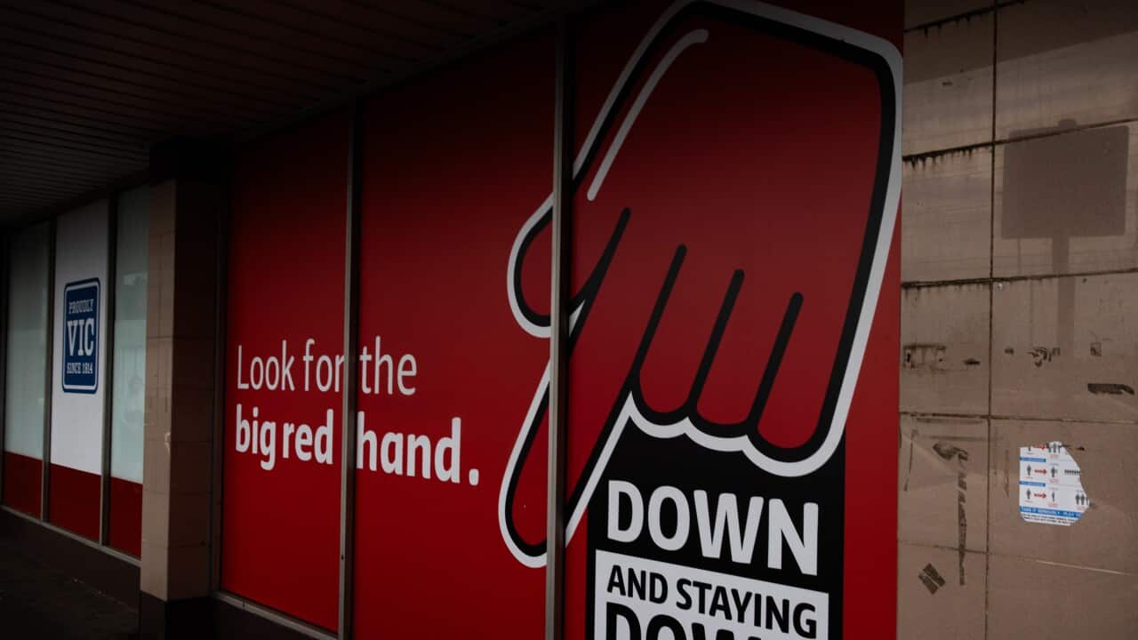 A large red storefront window display features a graphic of a giant red hand pointing down toward the text “DOWN AND STAYING DOWN,“ accompanied by the slogan “Look for the big red hand.“