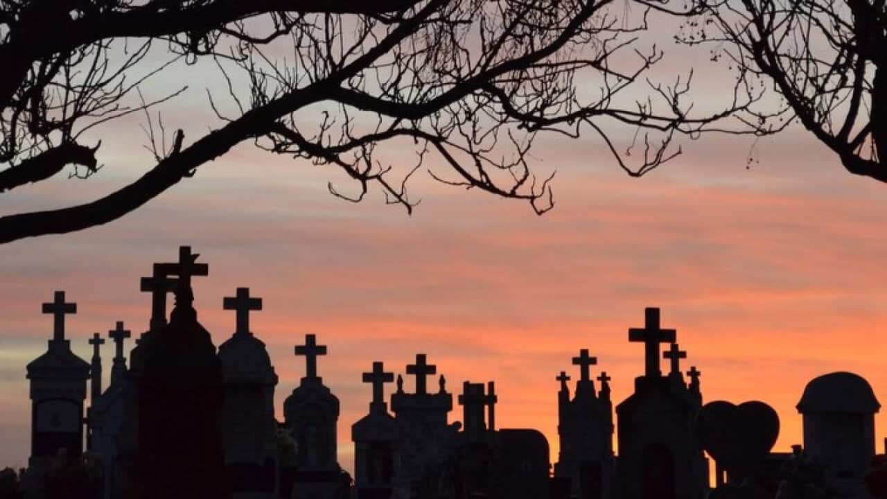 Silhouette Crosses On Tombstones By Bare Trees At Cemetery Against Sky During Sunset