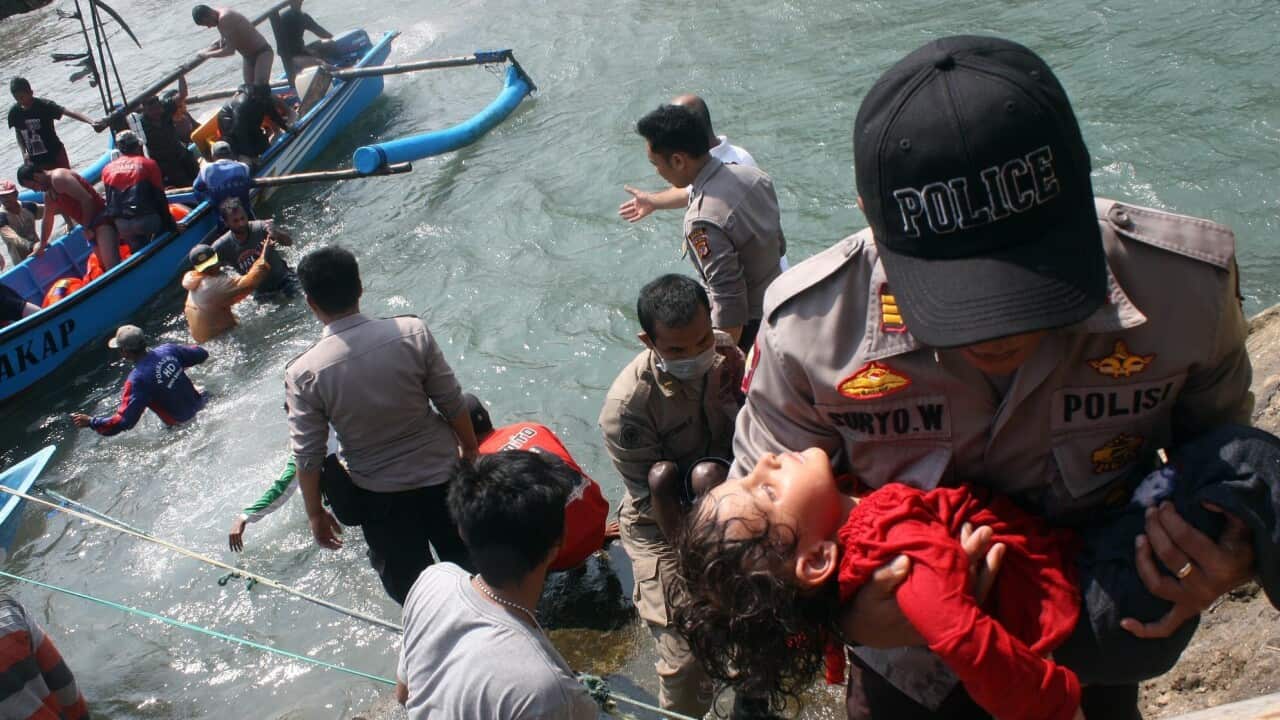 An Indonesian police officer carries an exhausted boy during a rescue operation after a fishing boat carrying mostly asylum seekers to Australia sank off Indonesia's Java Island. (AAP)