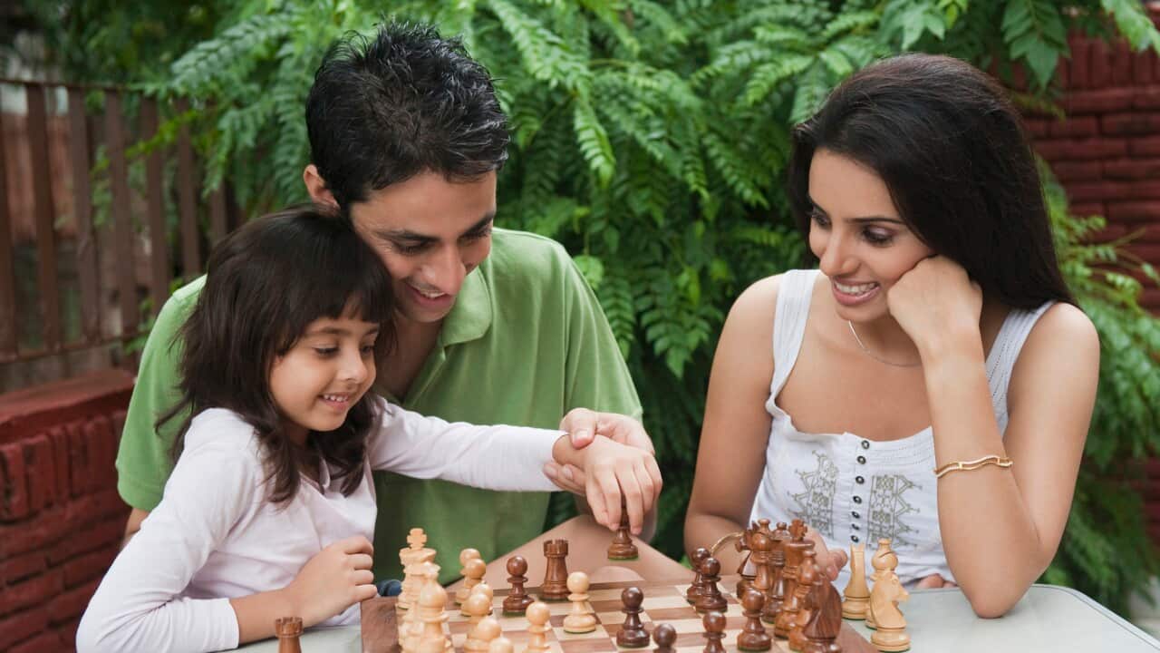 Girl playing chess with her parents
