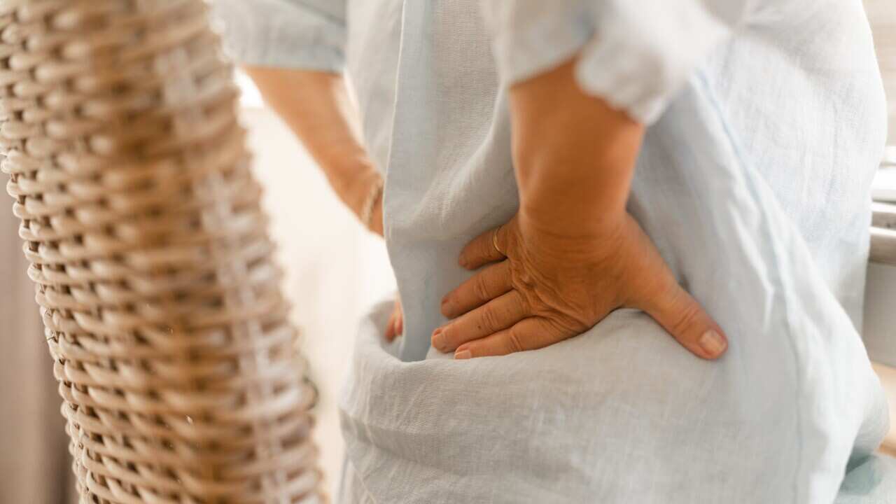 A woman massages the pain in her lower back