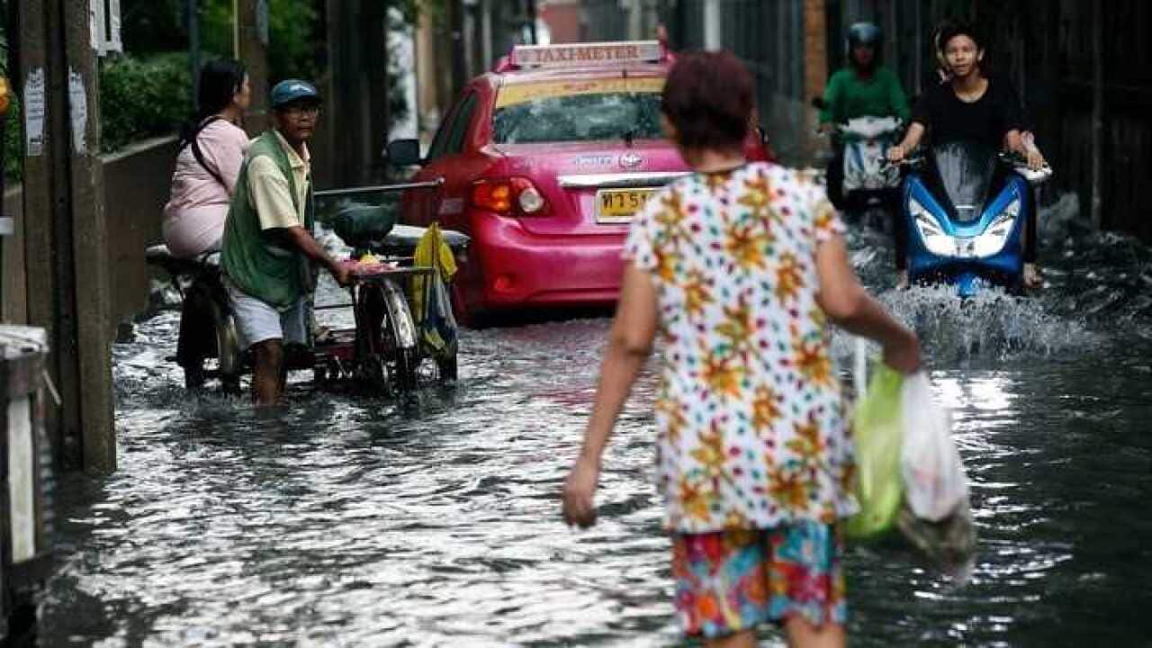 hai villagers wade through a flooded road after heavy rain in Bangkok, Thailand, 08 May 2018.