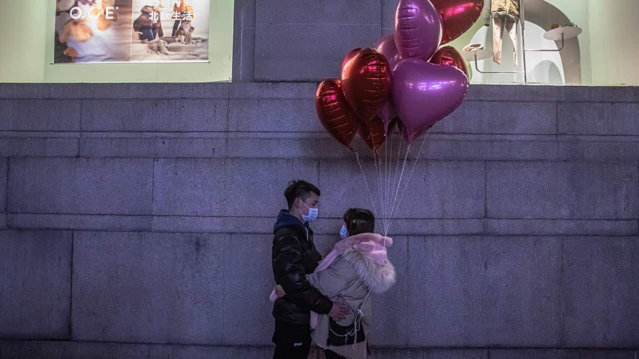 epaselect epa08913207 A couple wearing protective face masks pose for photos in a street on New Year's Eve in Wuhan, China, 31 December 2020. Life in Wuhan, a Chinese city of more than 11 million, which nearly a year ago became the epicenter of the corona