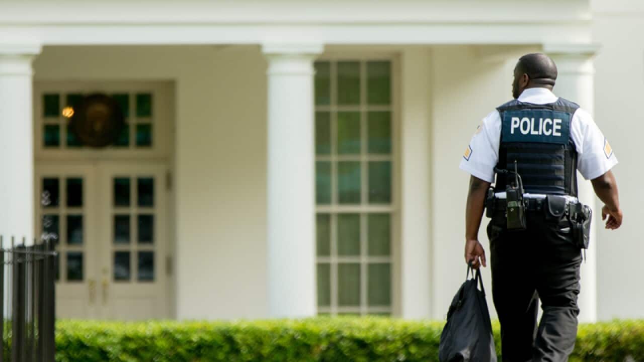 A uniformed Secret Service agent walks towards the White House