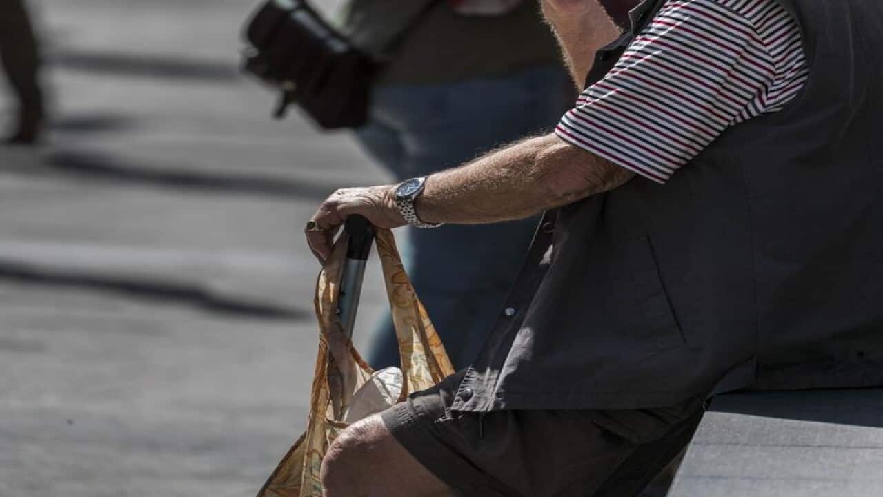 An elderly man sits on a bench, in Brisbane.