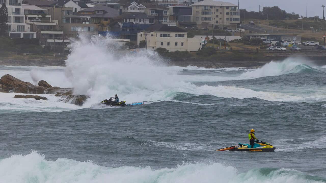 Surf lifesavers on jet skis search for a missing man in coastal waters.