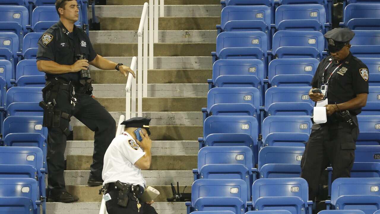 Police officers stand beside the remains of a drone that crashed into an empty section of seats at the U.S. Open tennis tournament in New York. (AP Photo/Kathy Willens)