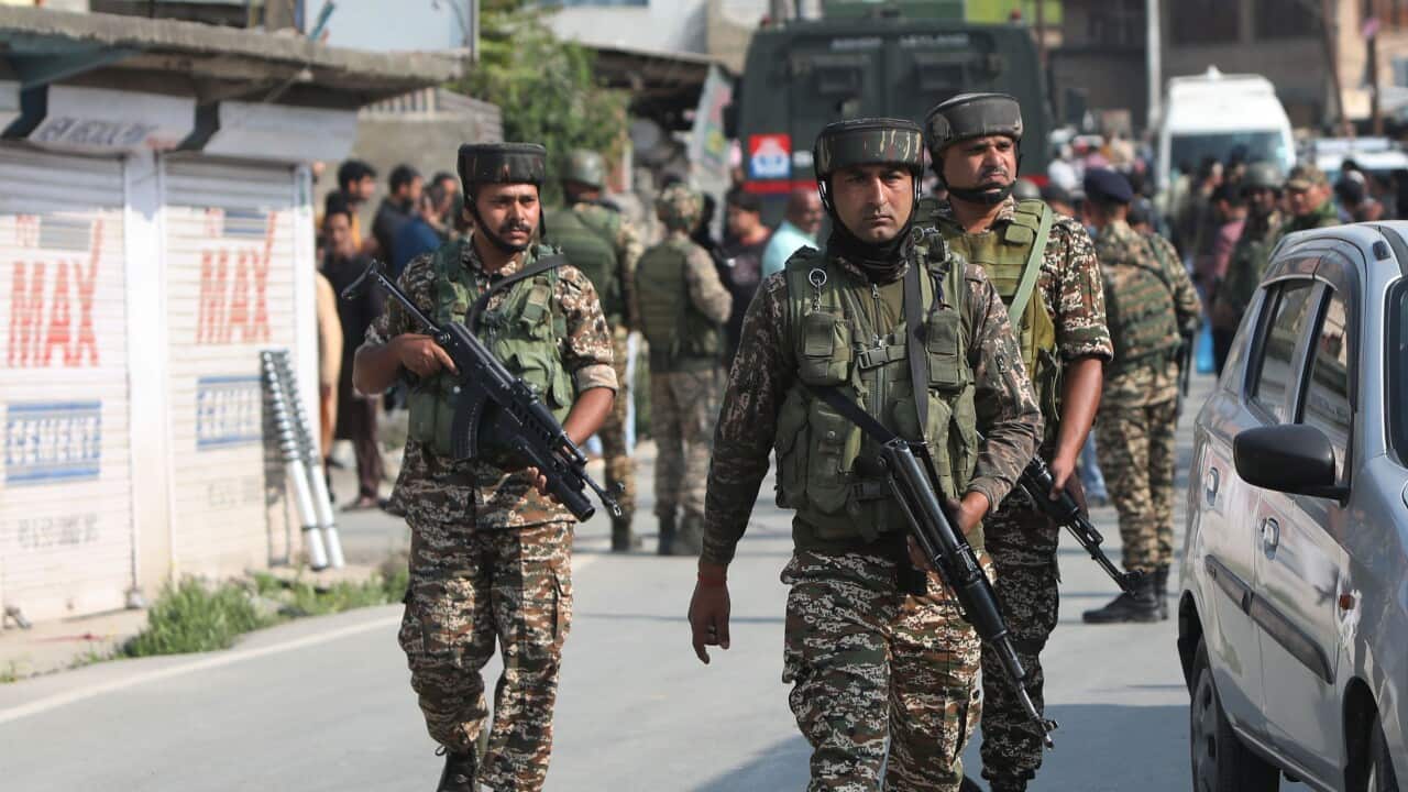 Security forces with guns patrol a road