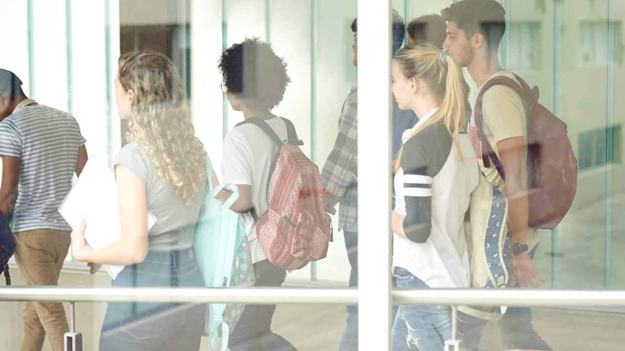 Students walking into a school corridor, viewed through a window