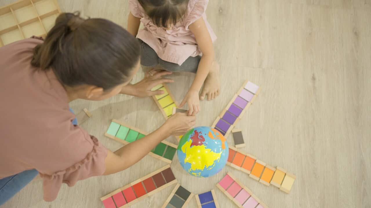 Preschool girl learning color with color box and model globe in Montessori education school