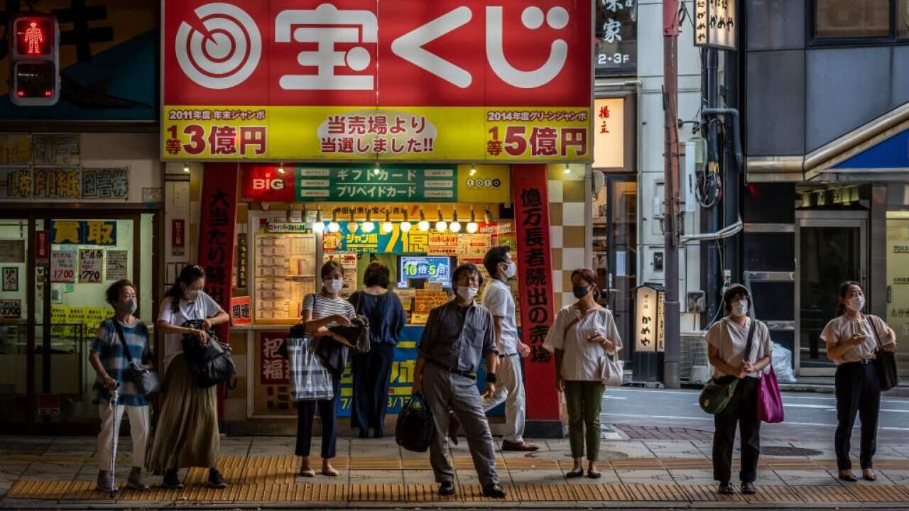 People wearing face masks wait to cross a street in Tokyo, Japan.