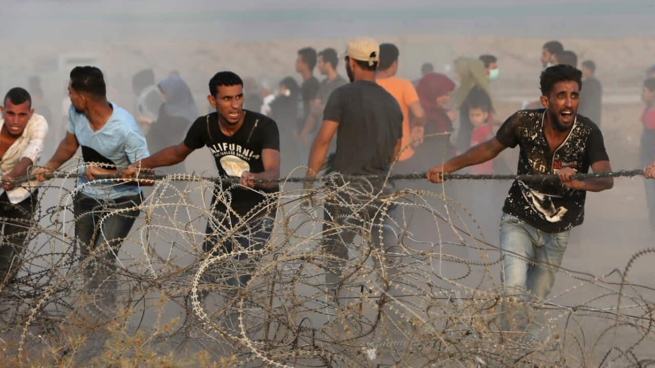 Protesters try to move part of the fence of the Gaza Strip border with Israel, during a protest east of Khan Younis, southern Gaza Strip, Friday, July 20