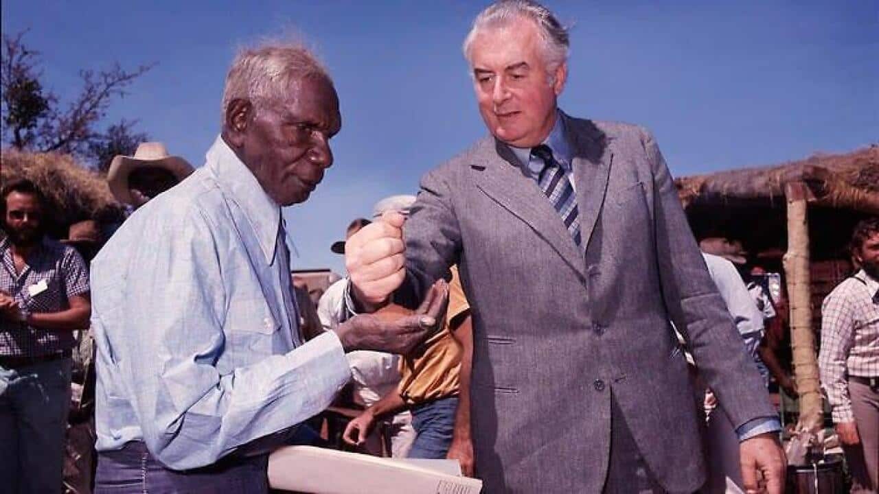 Gough Whitlam pours a soil in Vincent Lingiari's hands, marking the return of the Gurindji peoples' land.